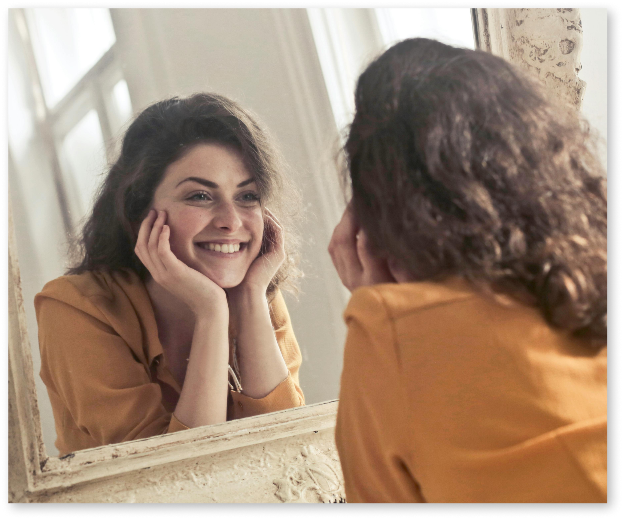 Woman smiling into a mirror.